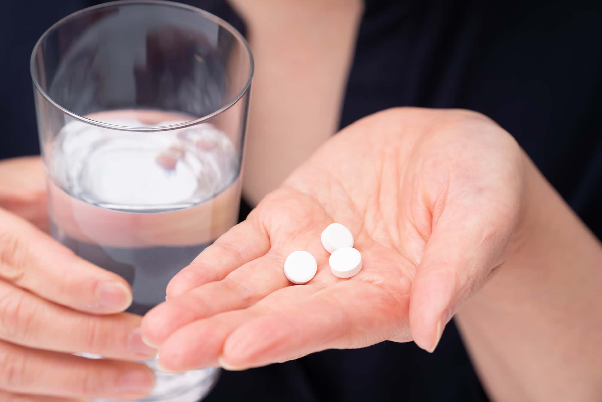 インプラント手術後の痛みを抑える為に自宅で処方された鎮痛剤を飲むイメージ