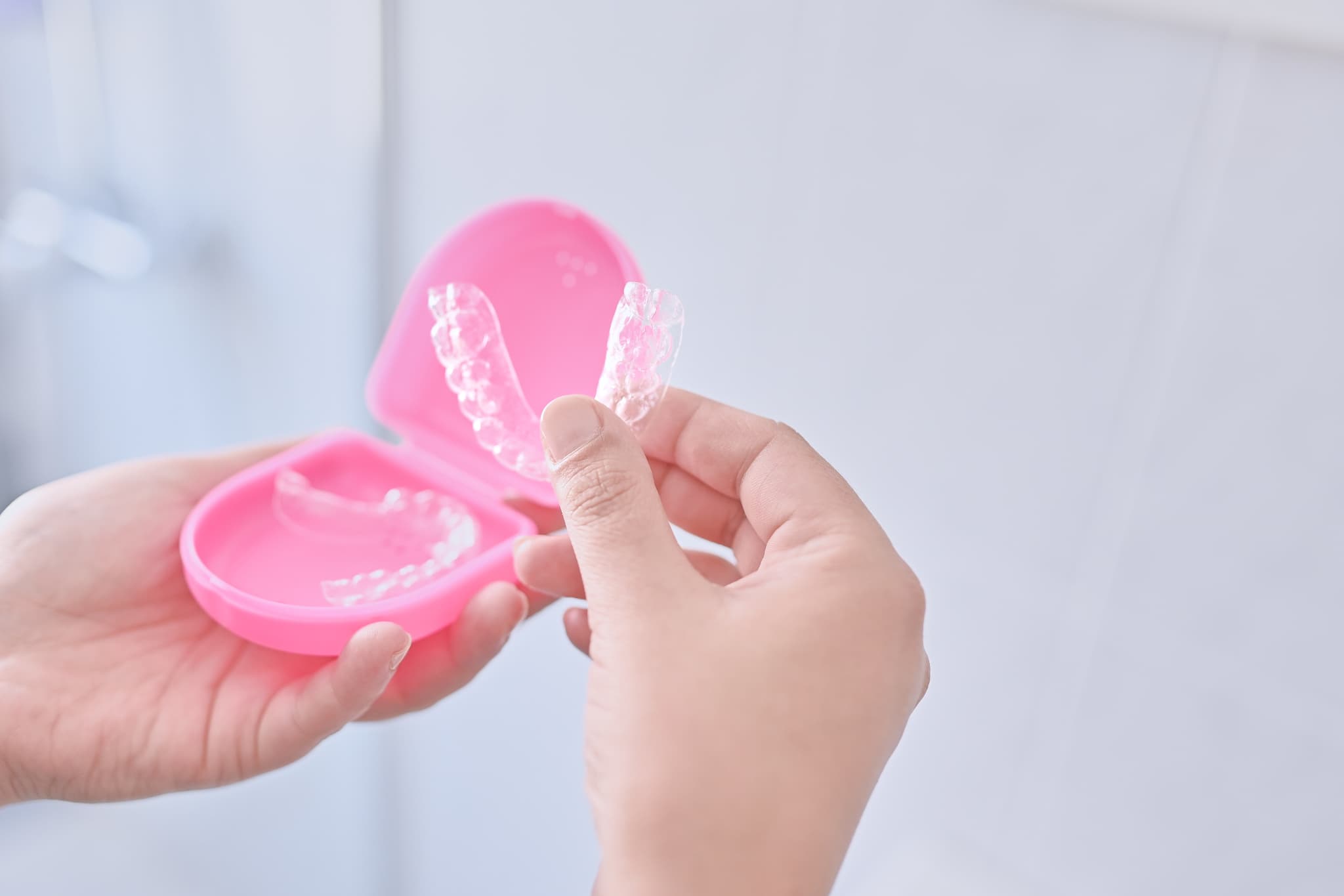 インビザラインのマウスピースをケースから取り出す女性の手元