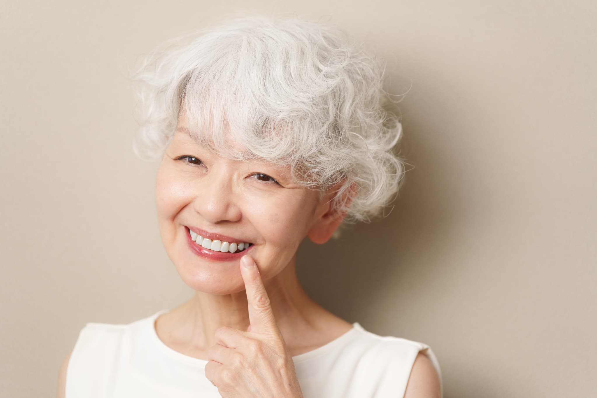 入れ歯を指さして笑顔を見せる高齢女性