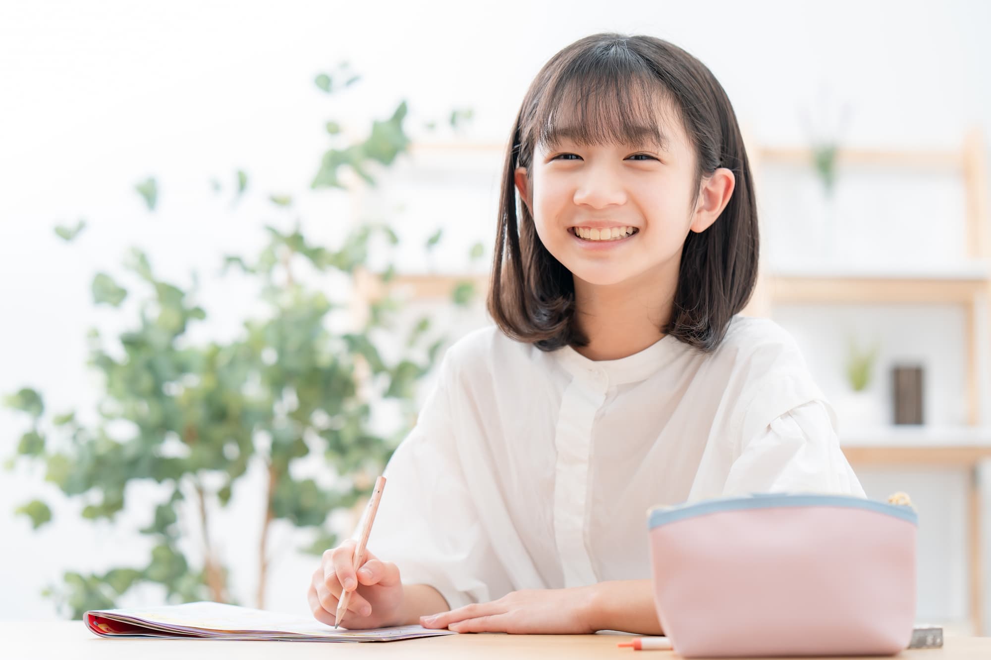 矯正して綺麗な歯並びになった女の子が笑顔で勉強をしているイメージ