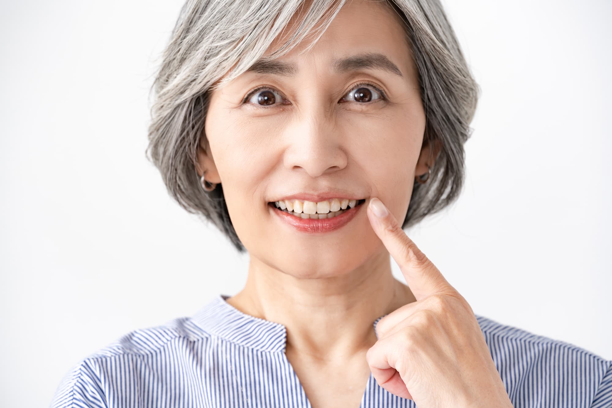 インプラントを指さして笑顔を見せる高齢女性
