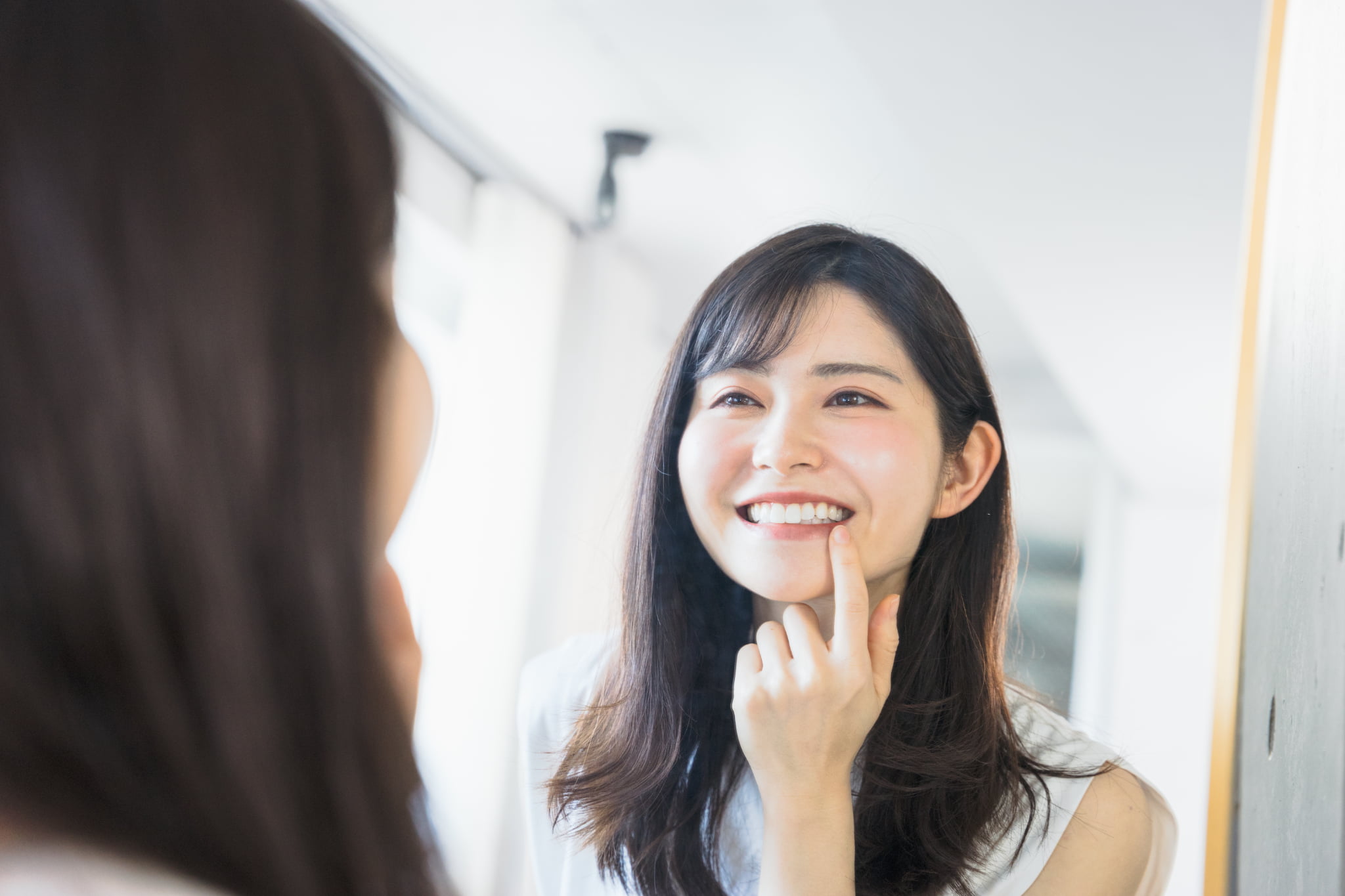 鏡を見てインビザラインの効果を感じ始めて喜ぶ女性