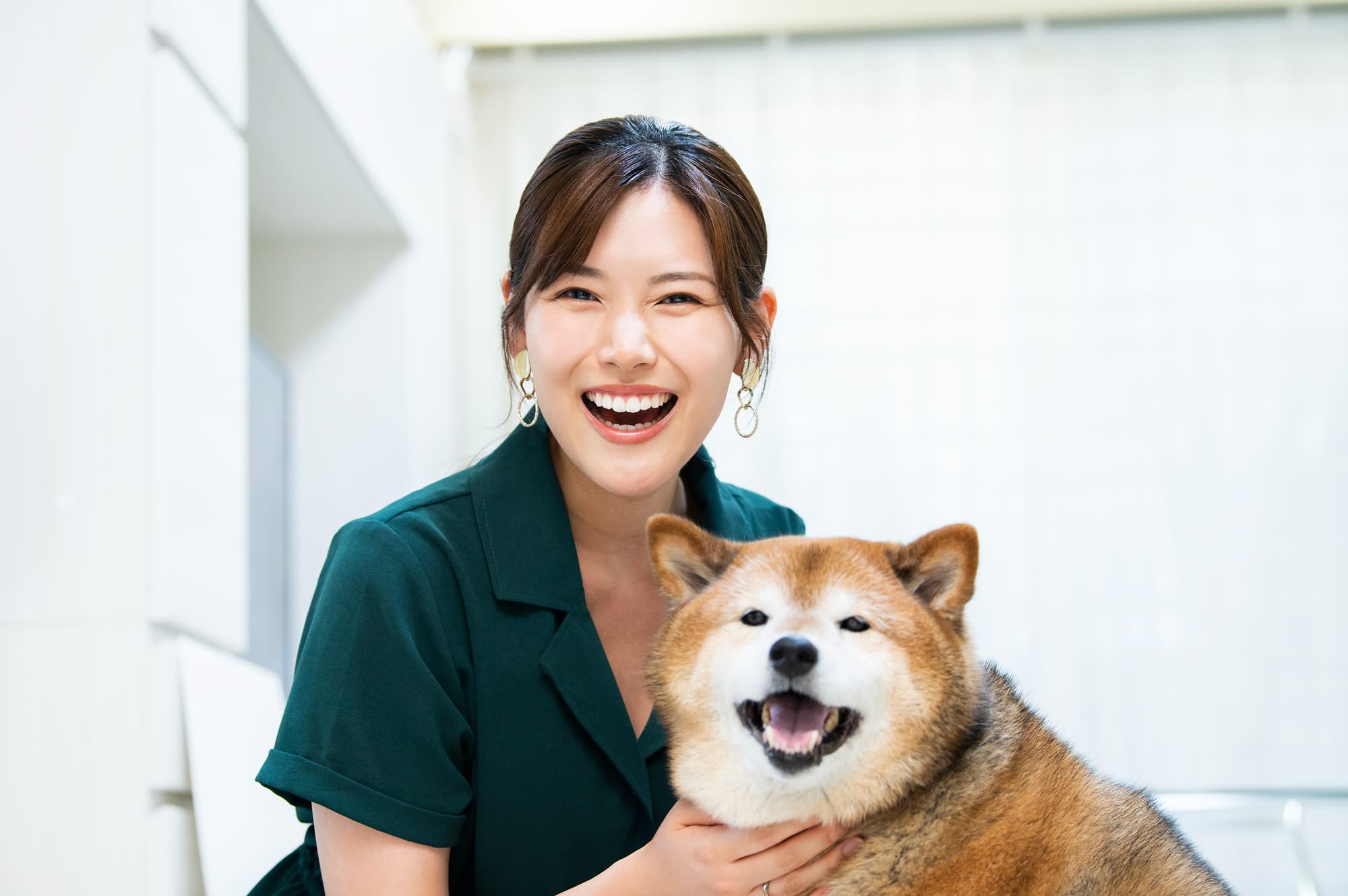ワイヤー矯正で整った歯並びになった笑顔の女性と愛犬