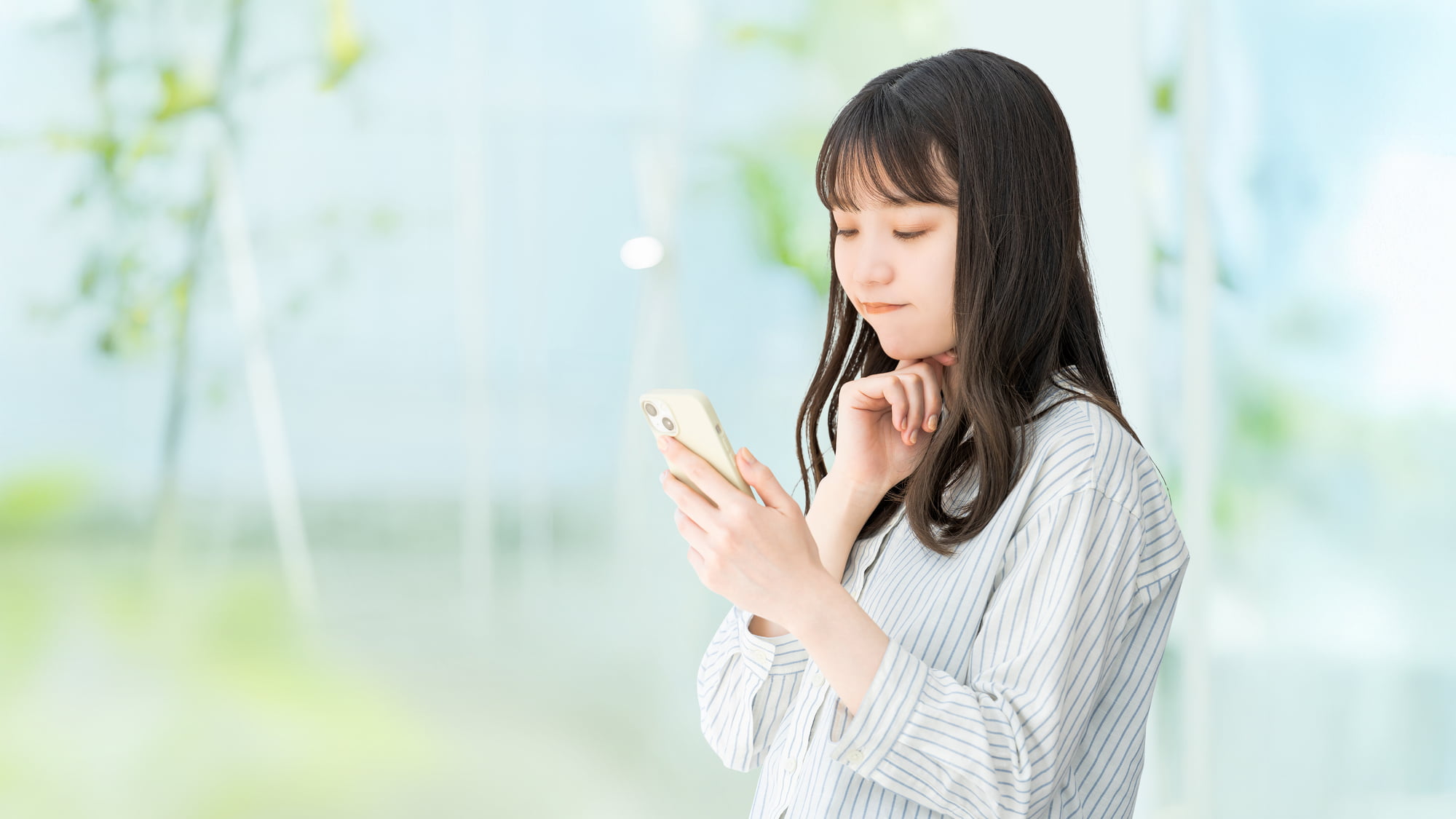 インビザライン矯正後の保定期間はどれくらいなのかスマホで調べる女性